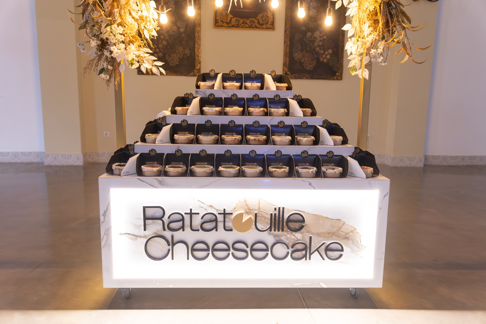 Stand iluminado de Ratatouille Cheesecake con tartas de queso individuales en una boda en Sevilla